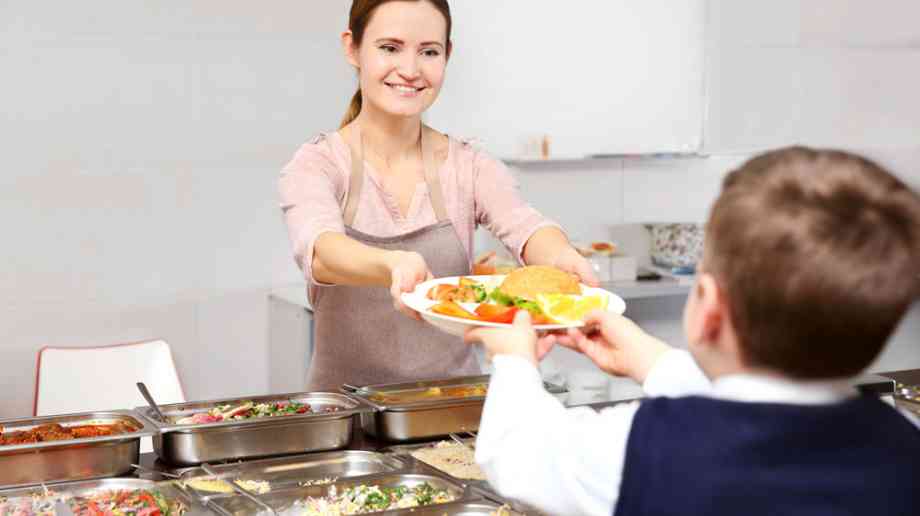 Dinner lady gives lunch to schoolboy.