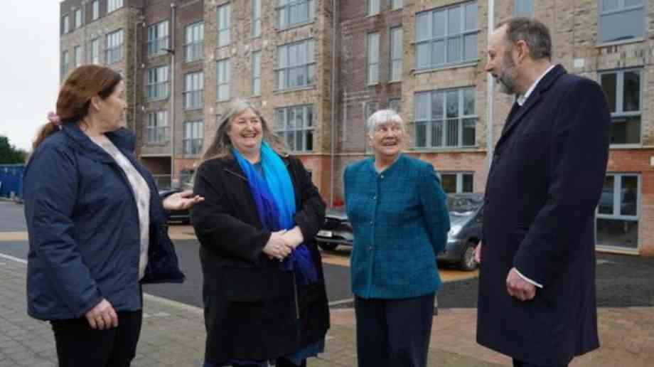 Four people stand on the roof of a new housing estate. 